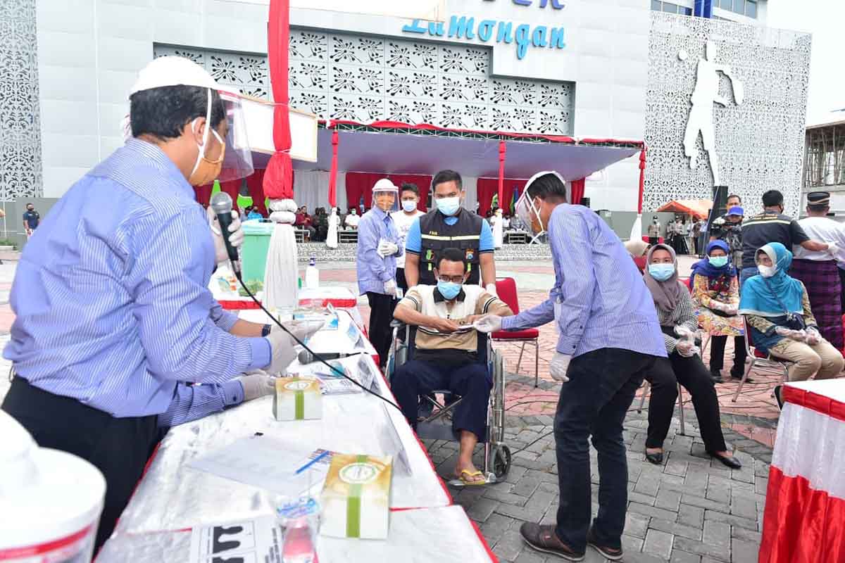 SIMULASI : Petugas sedang membantu seorang disabilitas dalam proses pemungutan suara. Inilah simulasi pengamanan dan pelaksanaan Pilkada tahun 2020 bertempat di halaman GOR Lamongan. (fjr) - Petugas Pilkada Wajib Pakai APD