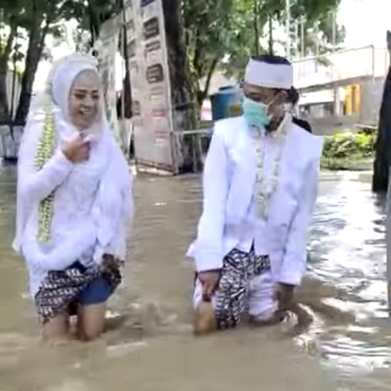 PENGANTIN BANJIR: Sepasang pengantin saat berjalan kaki terjang banjir menuju Kantor Urusan Agama (KUA) - Biar Kali Lamong Meluap, Ijab Tetep Berlangsung