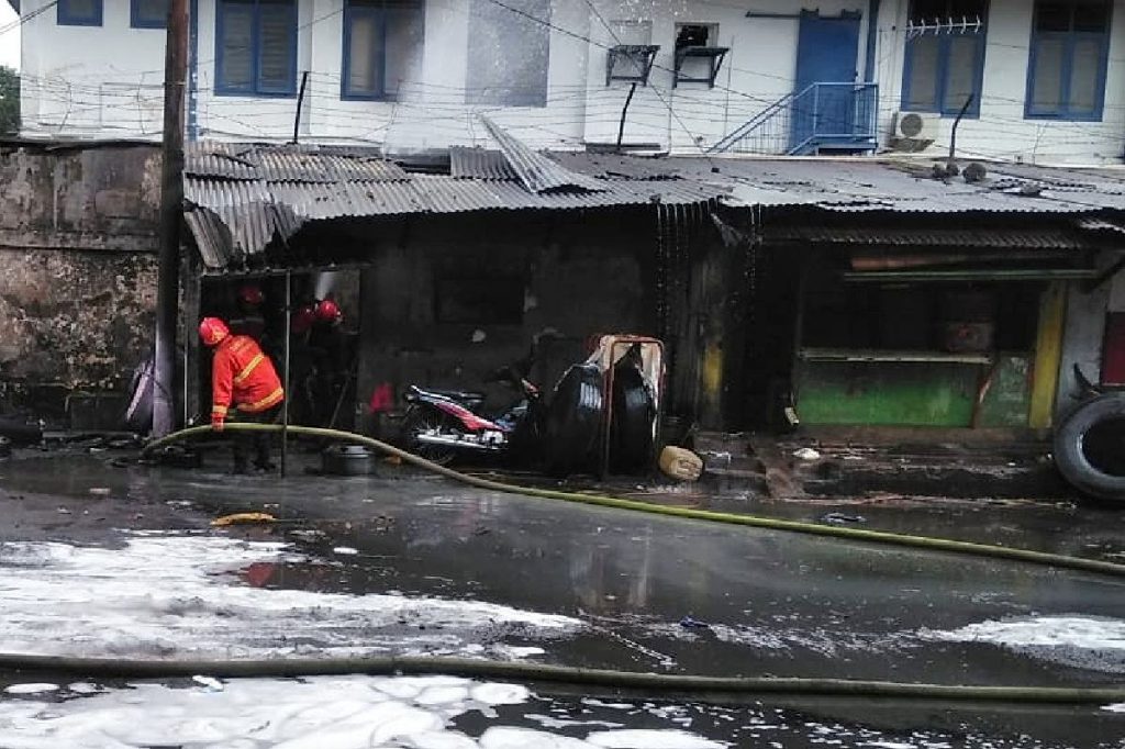 Petugas 'mendinginkan' lapak tambal ban yang terbakar. (ist) - Bikin Was-was, Truk Tangki Nambal Ban Terbakar Dekat Depo Pertamina