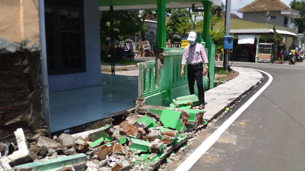 ROBOH: M.Nurhadi, warga Desa Candipari, menunjukkan lokasi pagar roboh milik warga dengan kondisi berantakan. (gus) - Kontraktor Proyek Peninggian Jalan Candipari Rusak Pagar Warga