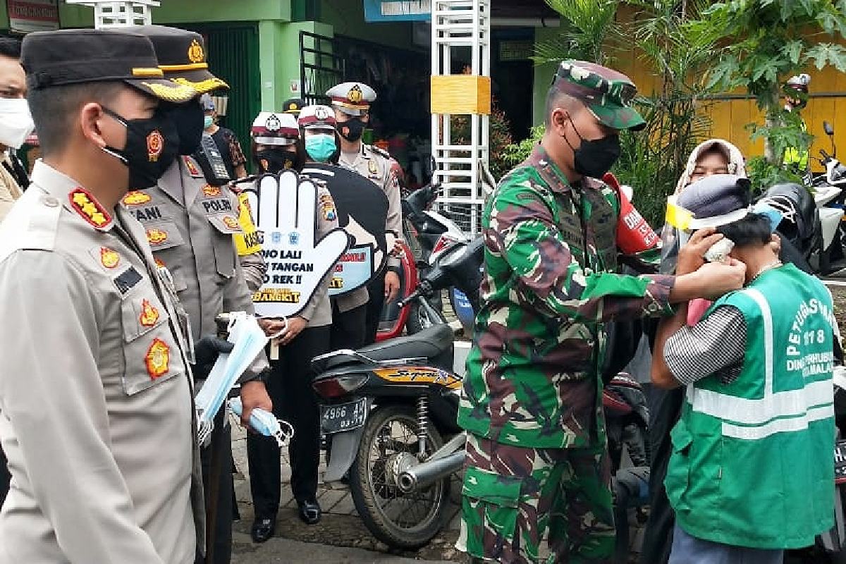 Dandim 0833 bantu kenakan masker. (ist) - Kapolresta Makota - Dandim 0833/Kota Malang Bagi Masker di Pasar Oro-Oro Dowo