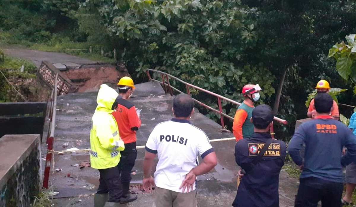 Petugas patroli beserta bersama BPBD Kabupaten Blitar, TNI dan Perangkat Desa Dawuhan memasang police line disekitar jembatan yang roboh dan mensterilkan area - Empat di Kabupaten Blitar Kecamatan Terdampak Bencana Alam