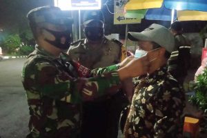 Petugas memakaikan masker bagi pelanggar tak kedapatan tak memakai masker. (ist) - Operasi Gabungan PPKM Klojen Sasar Gading Kasri - Galunggung