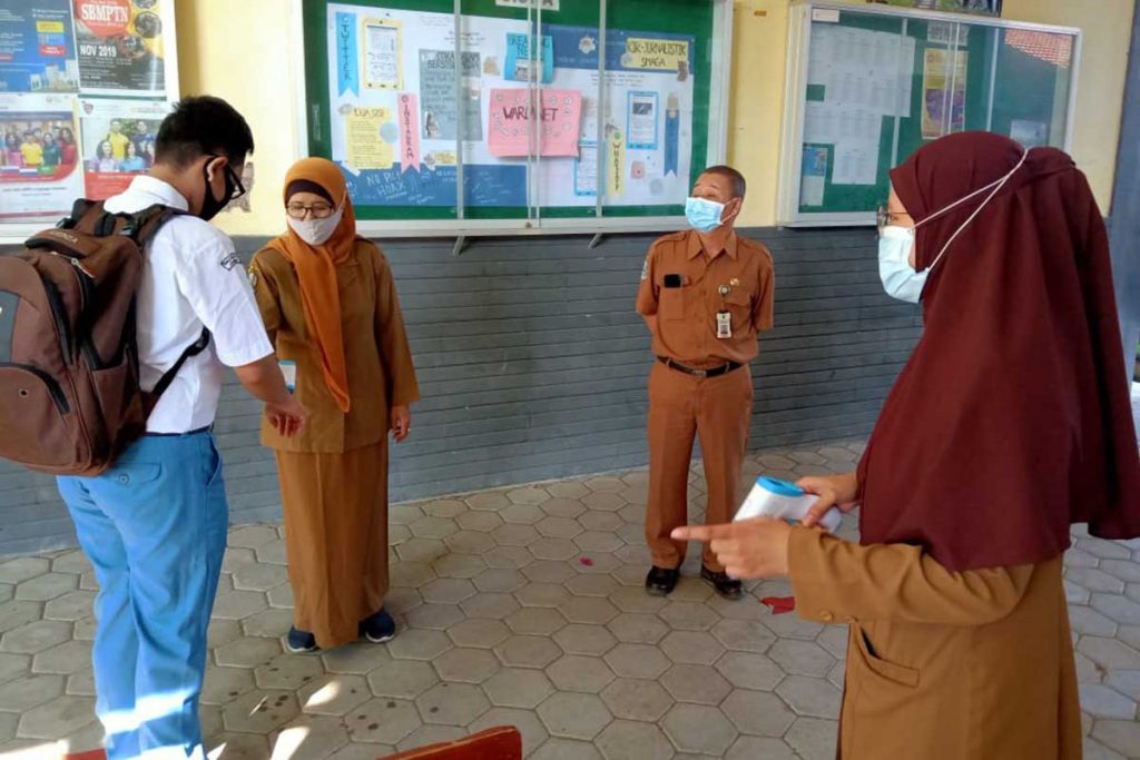 Cek suhu tubuh salah satu penerapan protokol kesehatan. (ist) - SMA 1 dan SMKN 5 Jember Uji Coba PTM Terbatas