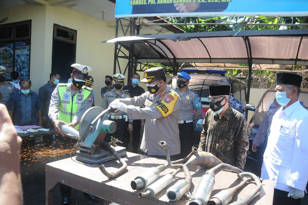 Kombespol Arman Asmara Syarifuddin saat memotong knalpot brong hasil razia bulan Maret hingga 2 April 2021. (ras) - Ribuan botol Miras dan Puluhan Knalpot Brong Dimusnahkan