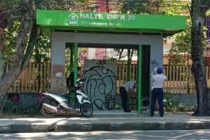 Petugas Dishub memasang stiker protokol kesehatan pada halte sekolah. (ist) - Antisipasi Kerumunan Jam Pulang Sekolah, Dishub Pasang Stiker Prokes