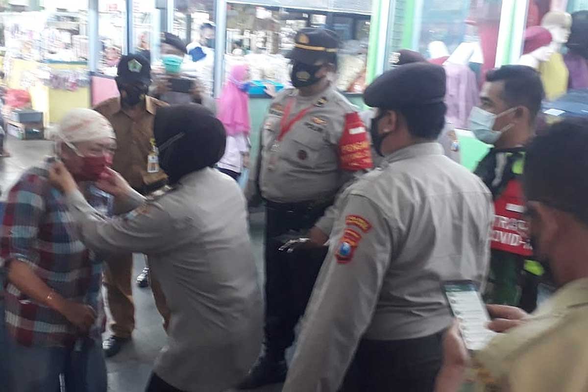 Petugas memakaikan masker. (ist) - Patroli PPKM Mikro, TNI-POLRI Blusukan Pasar Bunulrejo