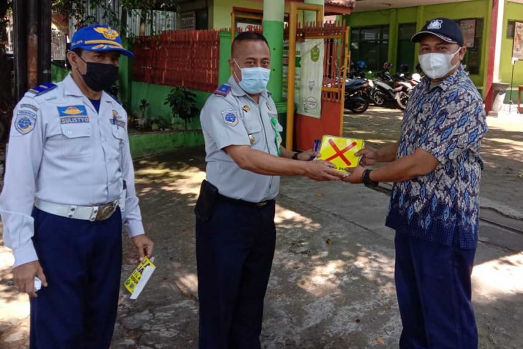 Petugas membagikan membagikan stiker kepada petugas sekolah. (ist) - Antisipasi Kerumunan Jam Pulang Sekolah, Dishub Pasang Stiker Prokes