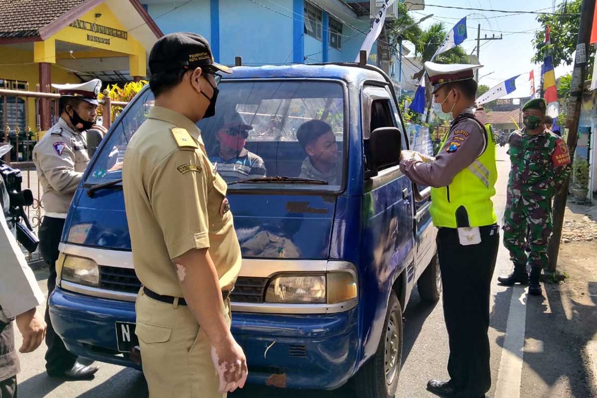 Petugas memberikan edukasi pentingnya penggunaan masker kepada keluarga pengendara mobil. (ist) - Cegah Mutasi India, Forkopimda Kota Malang Ingatkan Tetap Waspada