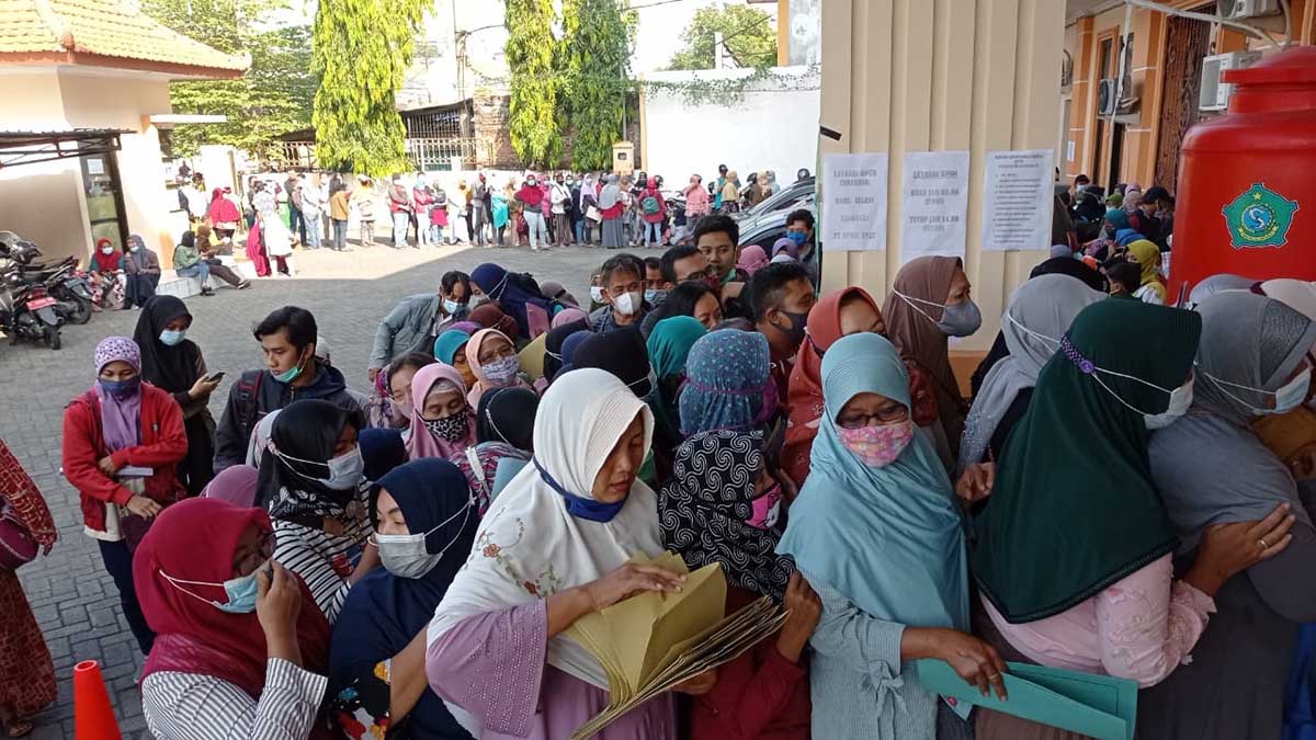 ANTRE - Ratusan calon penerima bantuan UMKM senilai Rp 1,2 juta antre panjang di depan Kantor Dinas Koperasi dan Usaha Mikro Pemkab Sidoarjo hingga di JL Raya Jaksa Agung Suprapto, Sidoarjo, Jumat (23/05/2021) - Pendaftar Bantuan UMKM Berjubel di Depan Kantor Dinkop Hingga Jalan Raya
