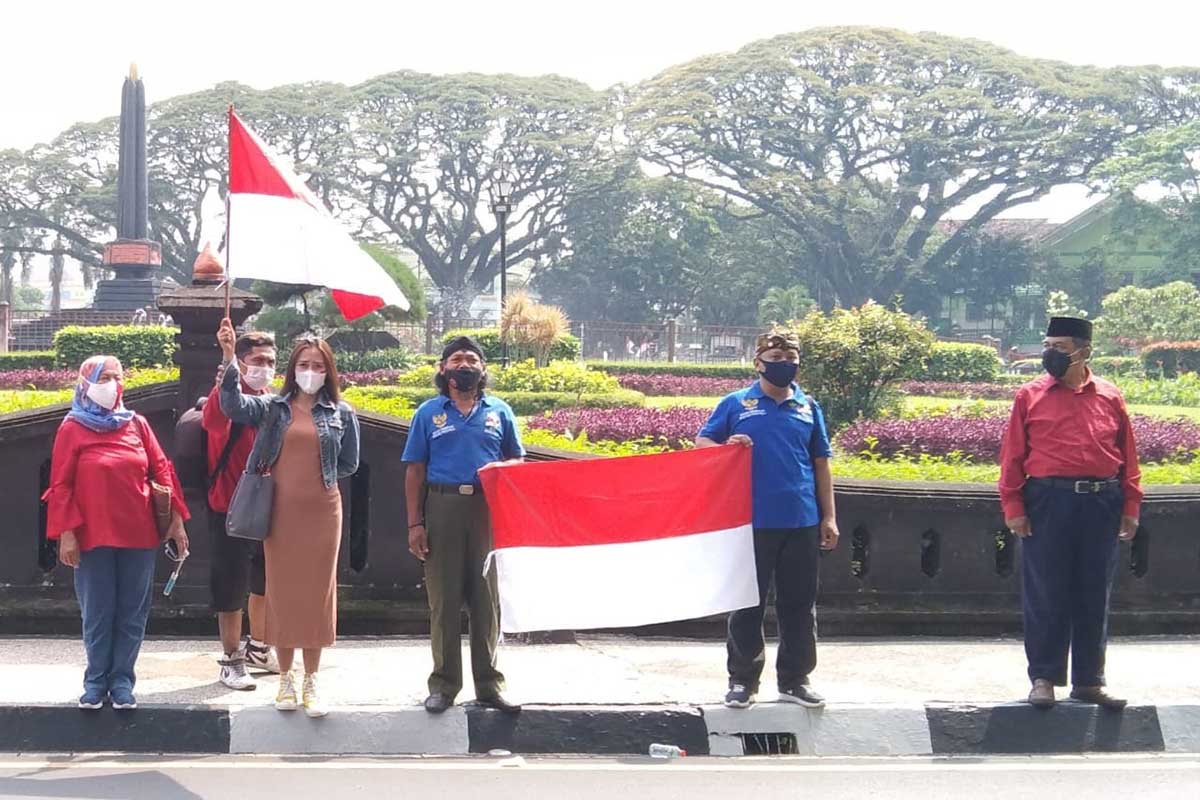 Beberapa peserta mengibarkan bendera merah putih di depan Tugu Malang. (ws1) - Peringati Hari Lahir Pancasila, 'Malang Bersatu' Aksi Damai Jogo Malang