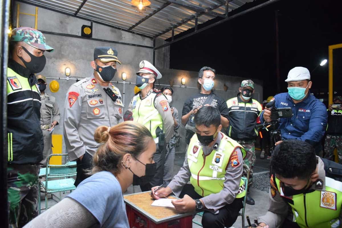 LANGGAR - Operasi Yustisi di kawasan JL KH Mas’ud, Kecamatan Buduran, Sidoarjo, petugas gabungan mendapati sejumlah kafe, warung dan pengunjung melebihi waktu operasional pukul 22.00 WIB hingga mereka langsung diberi sanksi, Senin (29/06/2021) malam - Operasi Yustisi Sasar Kafe dan Warung
