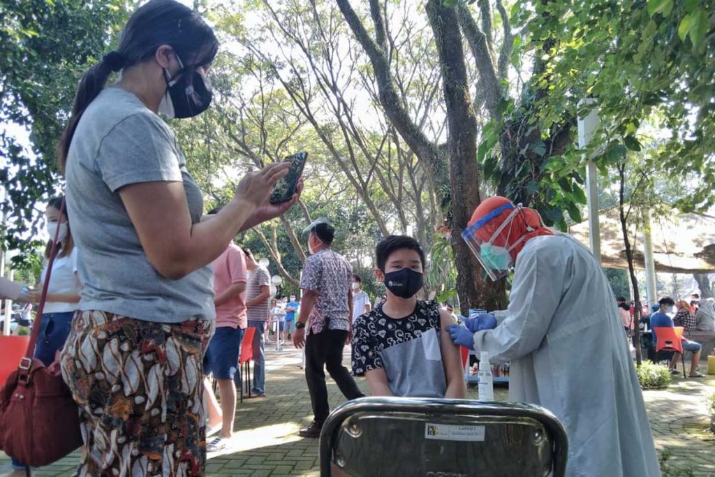 Salah satu penerima vaksinasi tampak tegang ditemani ibunya. (jaz) - 200 Anak Remaja Serbu Vaksinasi di Taman Slamet