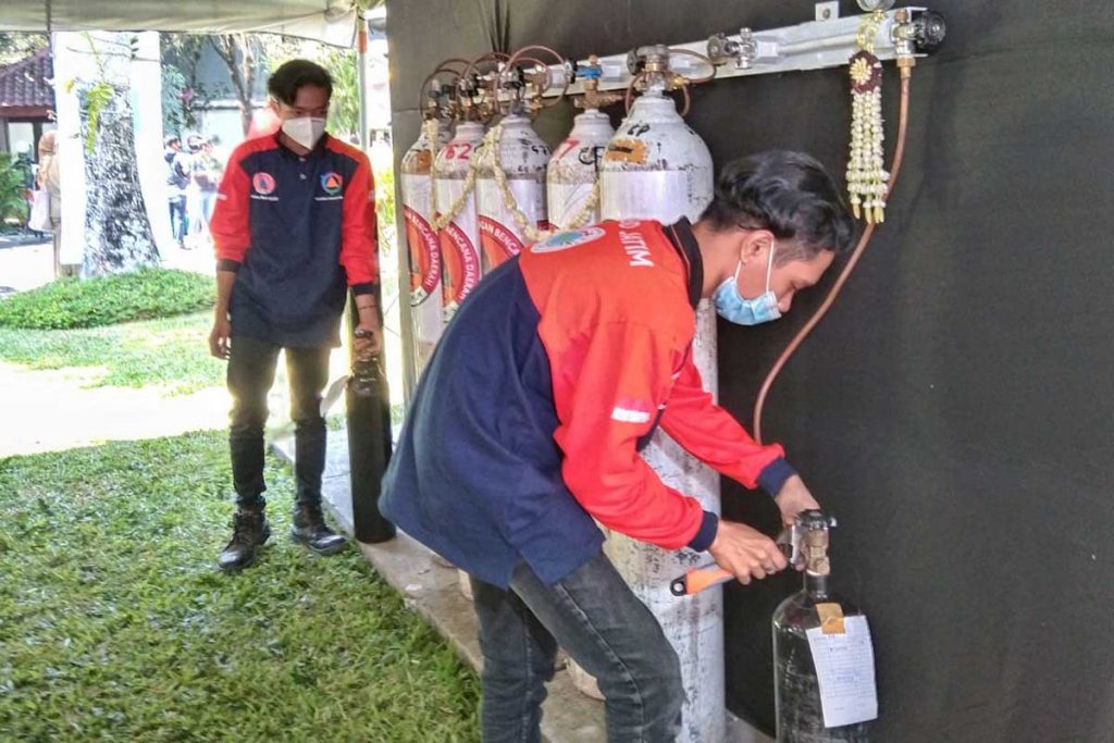 Salah satu petugas mengisi tabung gas oksigen. (jaz) - Khofifah Resmikan Isi Ulang Gas Oksigen Gratis, Minta Carikan Operator