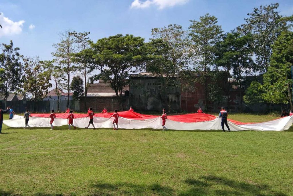 Proses pembentangan bendera oleh puluhan orang dan anak-anak. (jaz) - Dibalik Bendera Raksasa Malang, Begini Kendala Penjahit