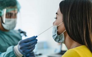 medical worker wearing personal protective equipment doing corona virus swab on female patient covid19 test and health care concept