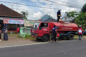 Petugas Pemadam Kebakaran saat memandang rumah milik Musyawarah, warga Dusun Krajan, RT 02 RW 05, Desa Kembiritan, Kecamatan Genteng, Jum'at (3/9/2021) siang. (Kuryanto) - Ditinggal Ke Pasar, Rumah Ludes Terbakar