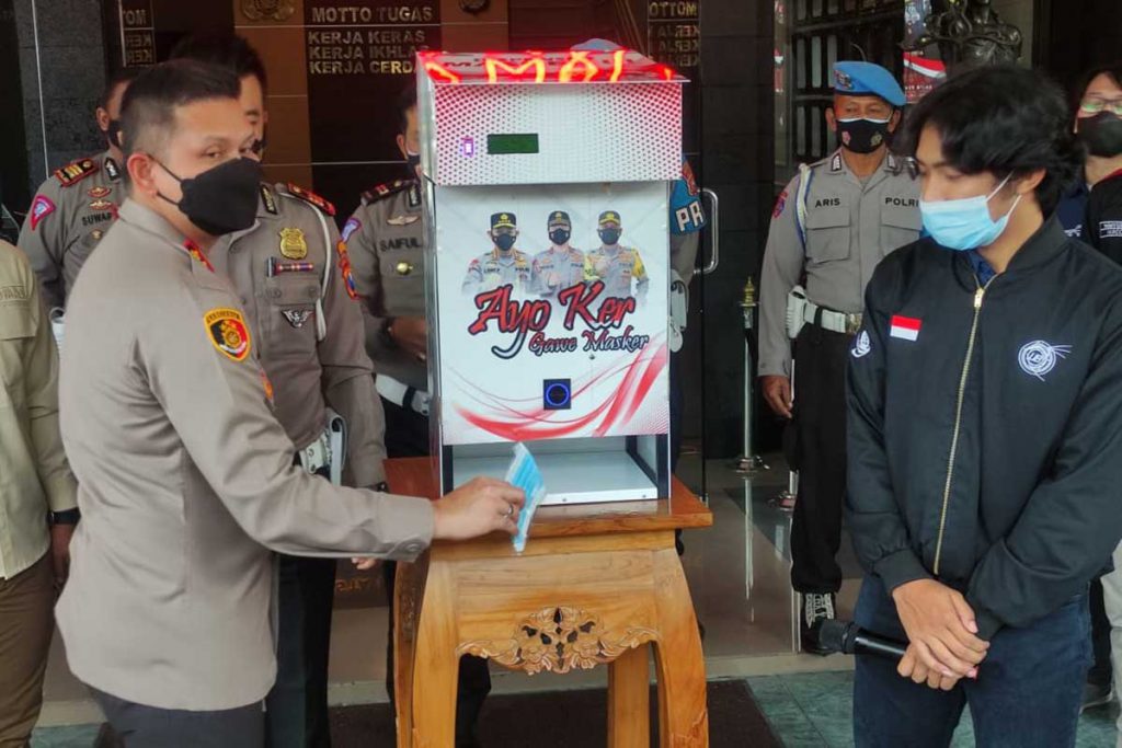 Kapolresta Malang Kota memperagakan pengambilan masker dari dispenser masker. (rhd) - Polresta Makota-Fakultas Teknik UB Luncurkan Dispenser Masker Pertama di Indonesia