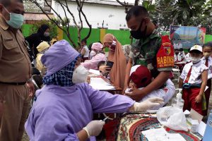 Anggota TNI menenangkan dan menyemangati siswa SD yang takut jarum suntik. (ist) - Vaksinasi Pelajar SD Kick Off di Kota Malang