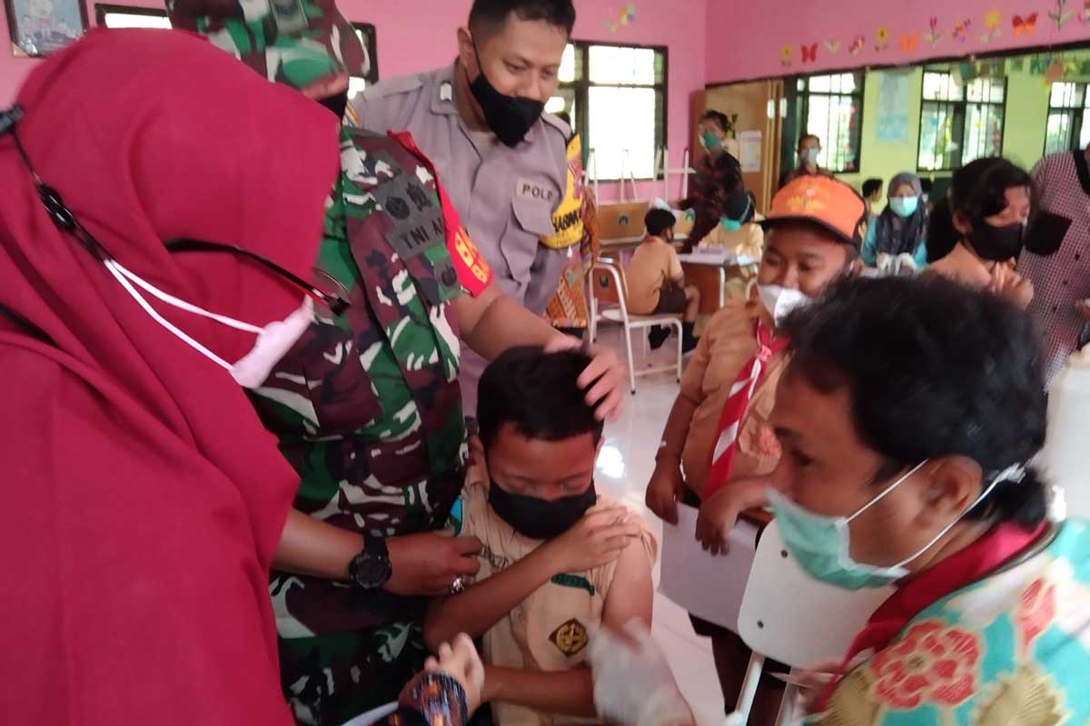 Petugas keamanan mendampingi vaksinasi anak. (ist) - Pemkot Malang Geber Vaksinasi Anak di Sejumlah Sekolah
