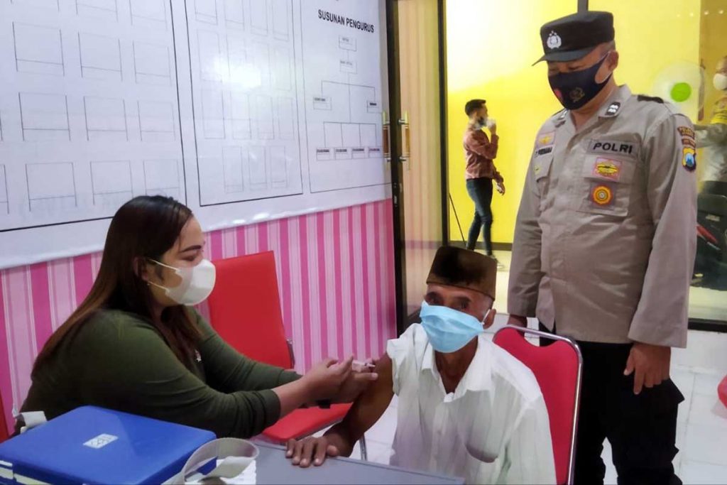 Aiptu Edi Purnama SH turut menyemangati dan mendampingi salah satu lansia yang divaksin. (yas) - Masifkan Vaksinasi Lansia, Polsek Ajung Bagi Sembako