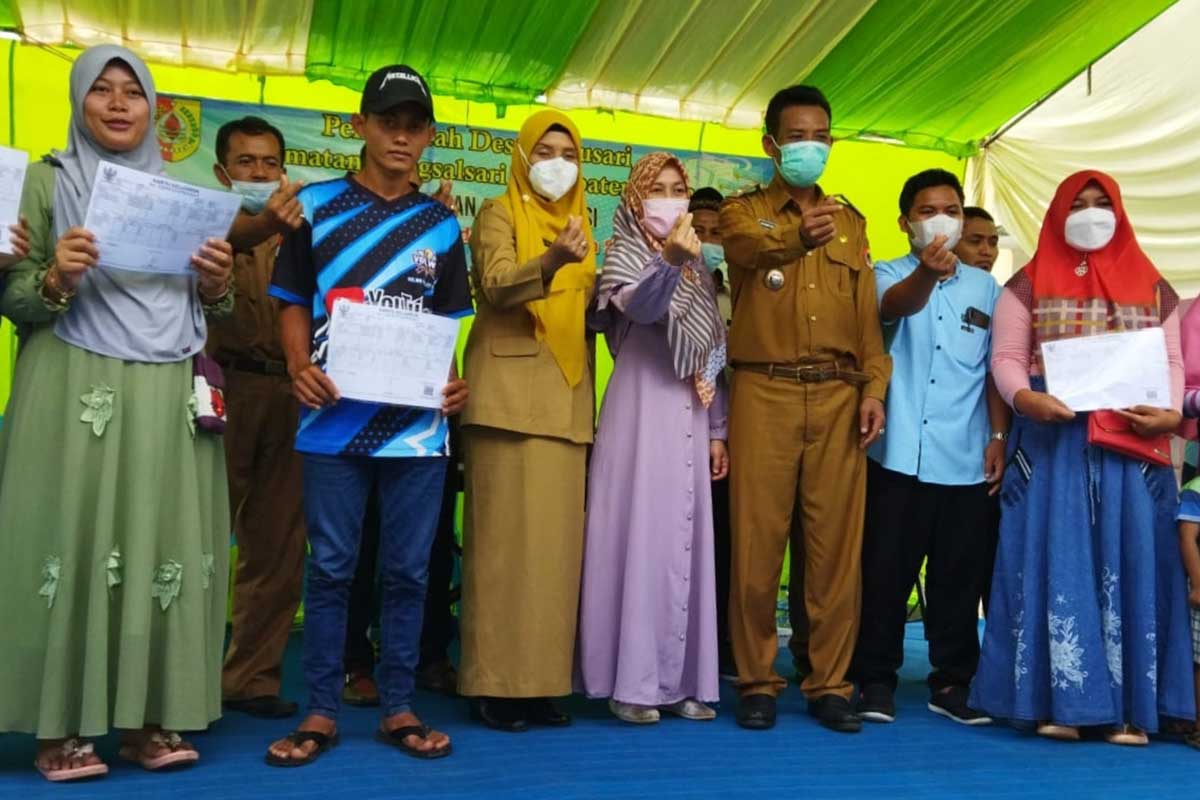 Penyerahan dokumen Adminduk simbolis dari Kepala Dispendukcapil Jember ke warga Desa Tugusari. (yas) - Kadispendukcapil Jember Serahkan Simbolis Dokumen Adminduk Warga Tugusari