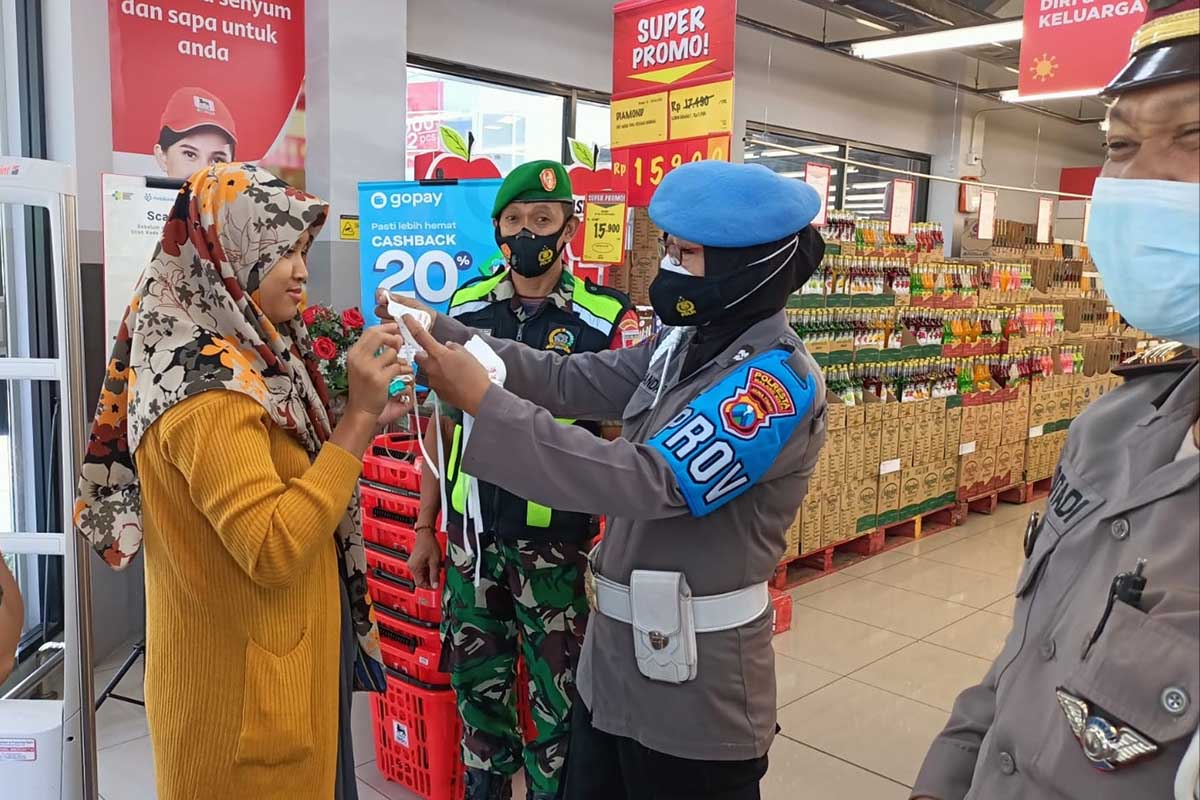 Tim Pamor Keris menegur dan mengenakan masker kepada pengunjung pasar modern. (ist) - Tim Pamor Keris Kedungkandang Operasi Tegakkan Prokes