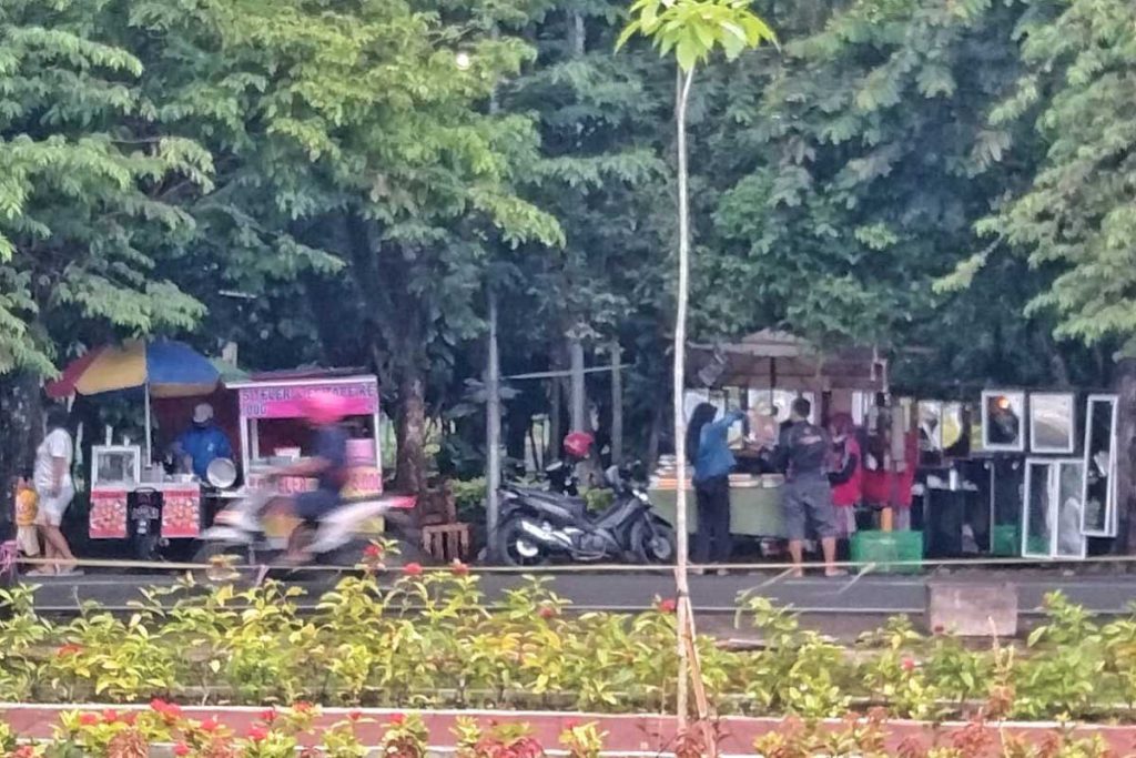 Jalan Mertojoyo yang berhadapan antara Taman Bunga Merjosari dan Taman Singa dipenuhi PKL. (jaz) - Warga Kota Malang Nikmati Taman Bunga Merjosari, Begini Penilaian Pengunjung
