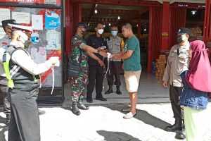 Petugas memberikan masker kepada pengunjung minimarket yang kedapatan tak bermasker. (ist) - Pamor Keris Kedungkandang Sosialisasi Prokes di Dirgantara Sawojajar