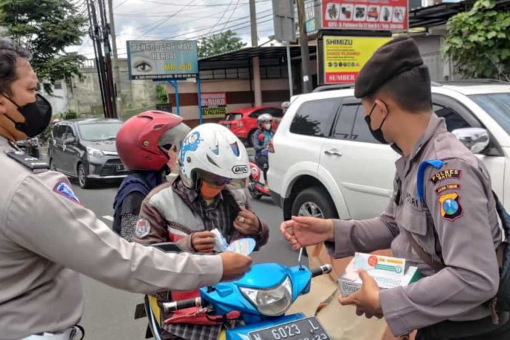 Petugas menempelkan stiker pada kendaraan roda dua. (ist) - Operasi Keselamatan Semeru, Satlantas Polres Batu Sasar Delapan Target Operasi dan Prokes