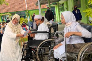 Kepala SLB ABD Negeri Kedungkandang Kota Malang, secara simbolis memberikan santunan anak yatim. (ws5) - Berbagi Keceriaan dalam Pondok Ramadan SLB ABD Negeri Kedungkandang