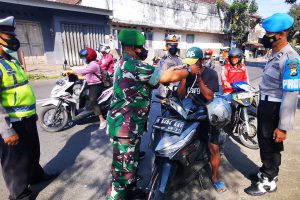 Petugas gabungan mengingatkan kepada pelanggar bahwa pandemi covid-19 belum berakhir, dengan memberikan masker. (ist) - Masifkan Pamor Keris, TNI-Polri Ingatkan Pandemi Covid-19 Belum Berakhir