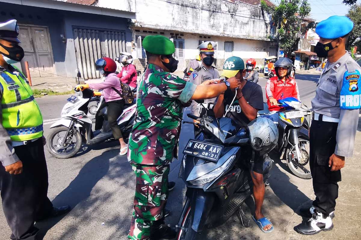 Petugas gabungan mengingatkan kepada pelanggar bahwa pandemi covid-19 belum berakhir, dengan memberikan masker. (ist) - Masifkan Pamor Keris, TNI-Polri Ingatkan Pandemi Covid-19 Belum Berakhir