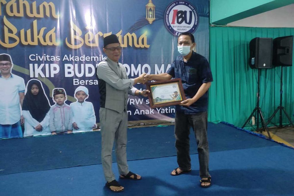 Rektor IBU Malang, Dr H Nurcholis Sunuyeko, MSi, menyerahkan penghargaan kepada Ketua PWI Malang Raya, Cahyono. (rhd) - IKIP Budi Utomo Malang Berikan Penghargaan Tokoh dan Santunan Anak Yatim