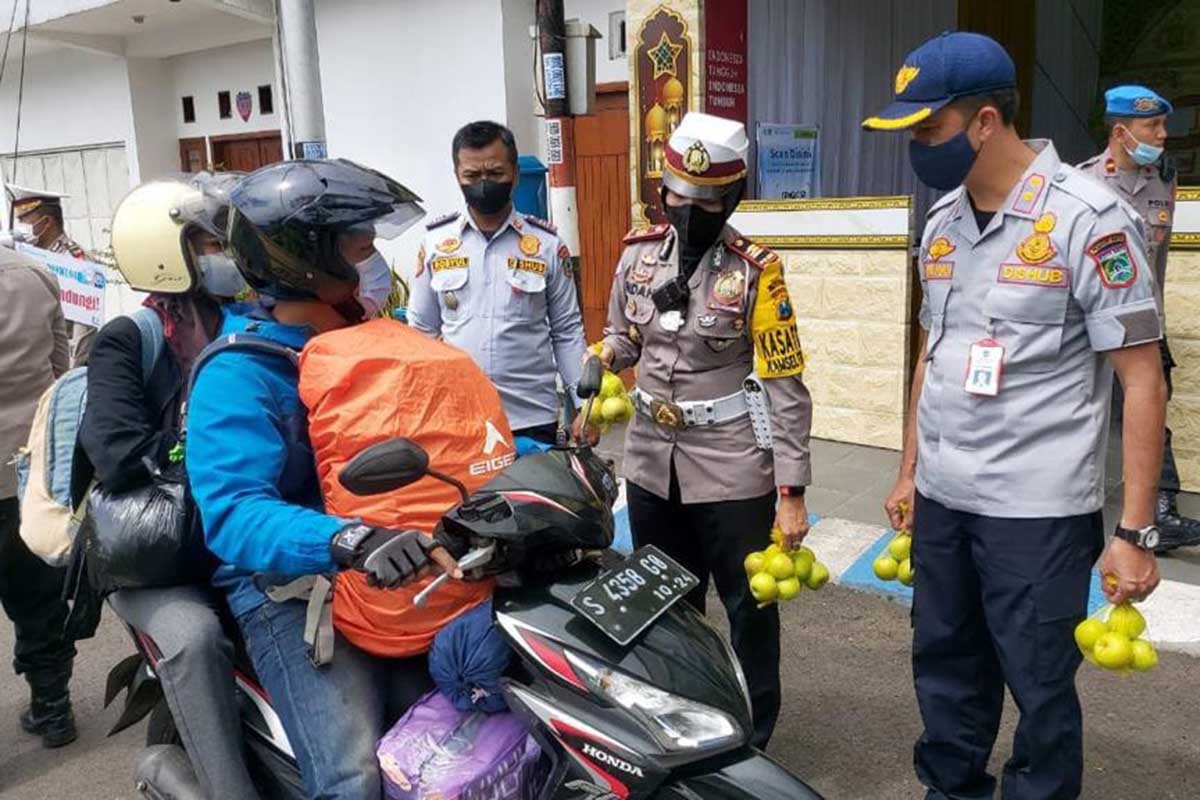 Kasat Lantas Polres Batu memberikan buah tangan apel kepada pengendara tertib. (ist) - Adil dalam Bertindak, Polres Batu Berikan Reward bagi Pemudik Tertib