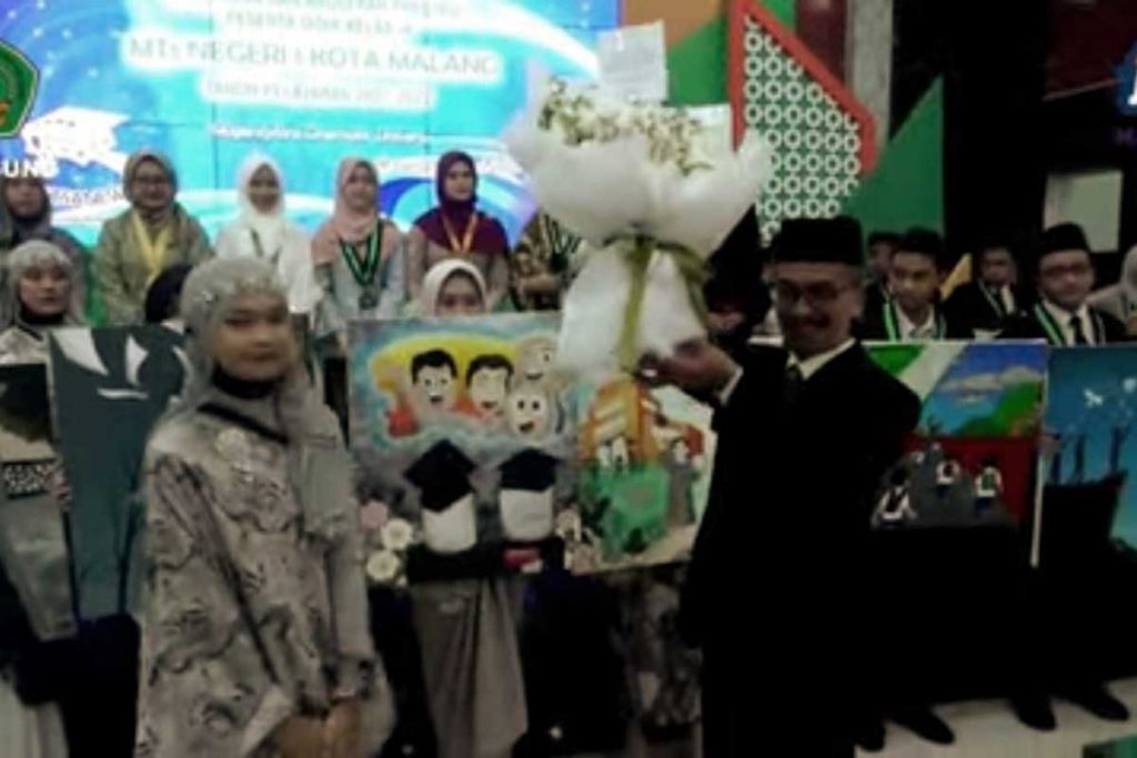 Kepala MTsN 1 Kota Malang menerima karangan bunga dari siswa lulusan kelas IX. (rhd) - Haru dan Bahagia, MTsN 1 Kota Malang Lepas 379 Siswa Kelas IX - Turut menyumbang 1.623 prestasi tahun pelajaran 2021/2022