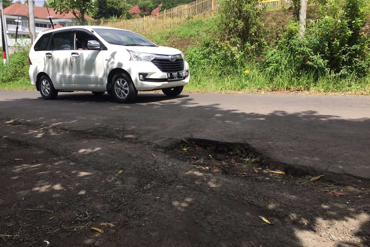 Kondisi jalan berlubang yang mengancam keselamatan pengendara. (dik) - Pembangunan Kereta Gantung Semakin Dekat, Dinas PUPR Jamin Jalan Aman Dilewati