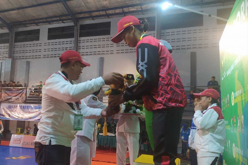 Pengalungan medali emas oleh Humas KONI Kab Malang, Toski Dermaleksana pada cabor gulat di venue Kab. Lumajang. (ist) -