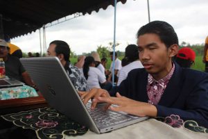 rizal tengah mengoperasikan laptop miliknya