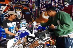 Sam Crebho sedang melayani pembeli. (dik) - Berkah HUT ke-35 Arema, Toko Jersey Diserbu Pembeli