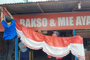 Sebuah usaha warung makan sedang memasang hiasan bernuansa merah putih. (dik) - Malas Pasang Bendera Merah Putih, Ini Akibatnya