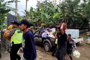 Anggota Polsek Pujon dibantu warga memindahkan bahan makanan bantuan dari Polres Batu. (ist) - Peduli Sesama, Polres Batu Salurkan Bansos Korban Banjir