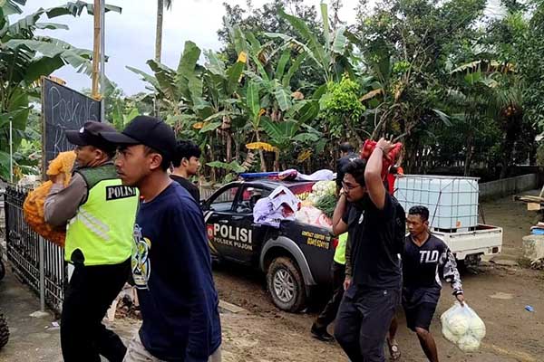 Anggota Polsek Pujon dibantu warga memindahkan bahan makanan bantuan dari Polres Batu. (ist) - Peduli Sesama, Polres Batu Salurkan Bansos Korban Banjir