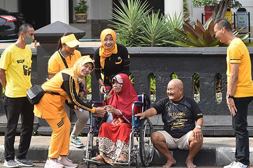 Peserta jalan sehat serentak HUT ke-58 Golkar bagikan bunga mawar kepada masyarakat. (ist) - Pecahkan Rekor MURI, Jalan Sehat Serentak Golkar Kota Malang Aksi Simpatik Tragedi Kanjuruhan