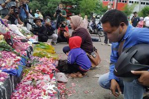 Warga masyarakat tengah berdoa dan menaburkan bunga di depan patung Tegar Sang Jawara. (ws6) - Aremania Apresiasi Kinerja Polri dengan Penetapan Enam Tersangka Tragedi Kanjuruhan