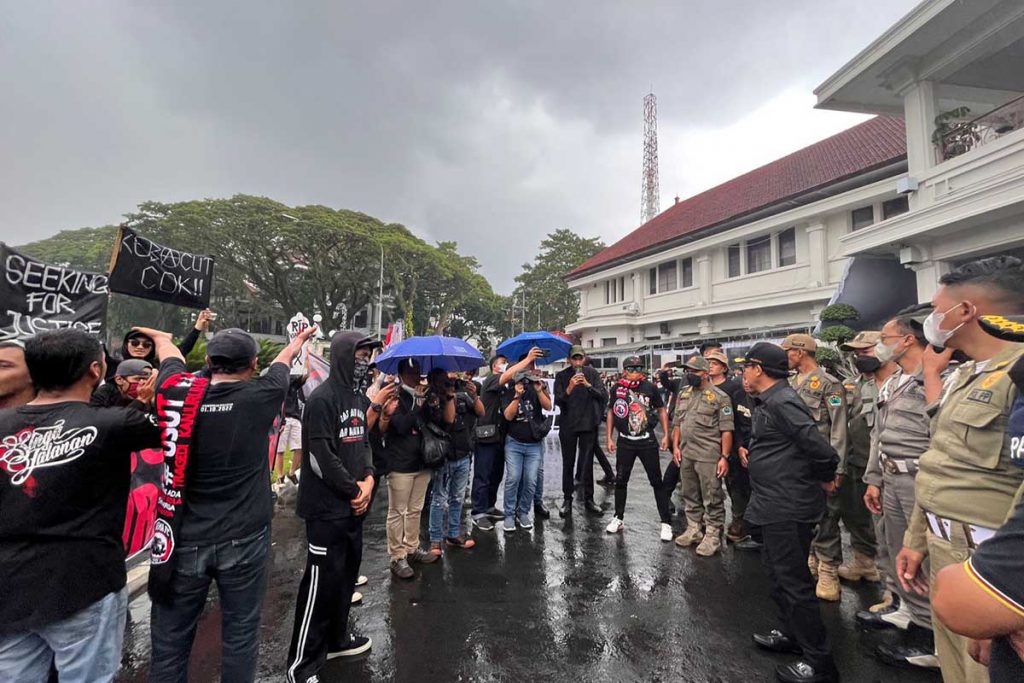 Aksi Aremania tetap berlanjut, meskipun diguyur hujan deras. (bim) - 40 Hari Tragedi Kanjuruhan, Ribuan Aremania Turun ke Jalan Tuntut Usut Tuntas