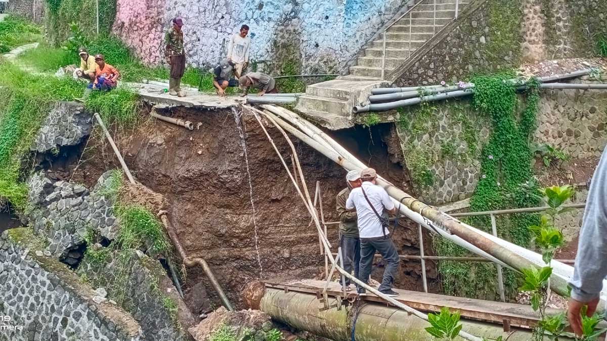BAHAYA: Warga langsung melakukan penyambungan pipa yang sempat tertimpa longsoran plengsengan di Desa Punten, kemarin. (ist) - Longsor, Jembatan dan Pipa Hippam di Punten Bumiaji Putus