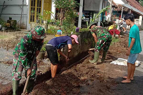 Babinsa Wonokoyo bersama warga karya bakti pembersihan saluran air dan jalan utama. (ist) - Babinsa Wonokoyo Karya Bakti Bersihkan Saluran Air dan Jalan Utama