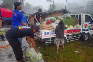 Tagana Kota Batu menurunkan bantuan sayur mayur dari kendaraan milik Dinsos untuk pengungsi. (ist) - Tagana Kota Batu Kirim Sayur Mayur ke Pengungsi Korban Erupsi Semeru