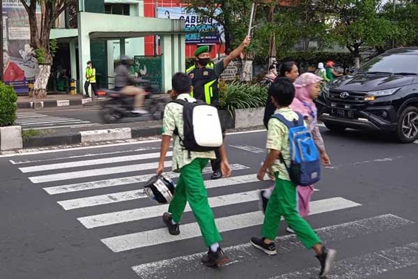 Babinsa Koramil Blimbing bantu menyeberang siswa SMP Kartika IV. (ist) - Beri Rasa Aman, Babinsa Koramil Blimbing Bantu Menyeberang Siswa SMP Kartika IV